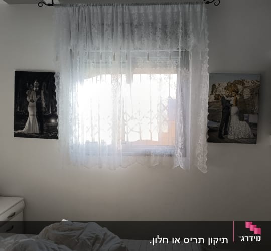 חדר שינה עם וילון לבן ותמונות על הקיר